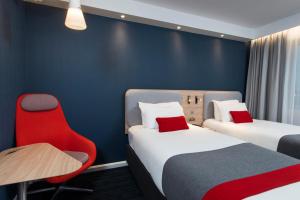 a room with two beds and a red chair at Holiday Inn Express London Greenwich by IHG in London