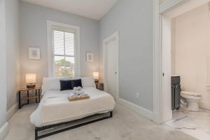 a white bedroom with a bed and a toilet at Historic Benton Park Townhome in Soulard