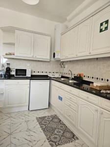 een keuken met witte kasten en een witte koelkast bij Maria Saudade Apartamento in Sintra