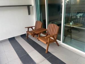 two wooden chairs sitting on a porch next to a table at Muji Wi-Fi Aircond HomeStay in Sandakan