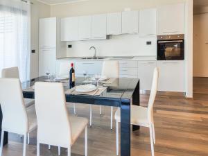 a kitchen with a dining table and white cabinets at Homiday - WaterFront Montesilvano in Montesilvano