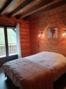 1 dormitorio con 1 cama en una habitación con paredes de madera en Chalet de Manigod, en Manigod