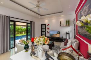 een woonkamer met een bank en een tafel met bloemen bij VILLA MARAMA | Private Pool | Kokyang Estate by Tropiclook | Naiharn beach in Nai Harn Beach