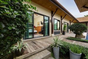 een huis met een houten terras met planten bij VILLA MARAMA | Private Pool | Kokyang Estate by Tropiclook | Naiharn beach in Nai Harn Beach