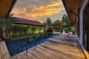 uma piscina com 2 espreguiçadeiras num deque de madeira em VILLA MARAMA | Private Pool | Kokyang Estate by Tropiclook | Naiharn beach em Praia de Naihan