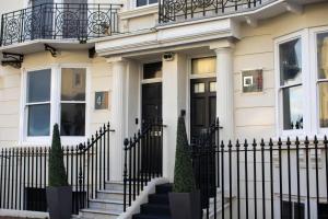 a white house with a black fence at Square Townhouse in Brighton & Hove