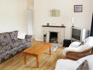 een woonkamer met een bank, een tafel en een tv bij Daffodil Cottage in Grange