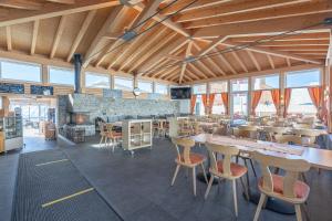 un comedor con mesas, sillas y ventanas en Appartmenthaus Bergfreund en Fiesch