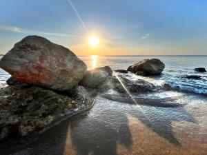a group of rocks on the beach with the sun setting at Villaggio Mondial Camping in Metaponto