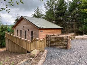 a small wooden building with a wooden fence at Holly Berry Lodge with Hot Tub in Cupar