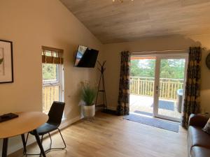 a living room with a table and a sliding glass door at Holly Berry Lodge with Hot Tub in Cupar