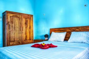 KJ Purple House Senggigi في سينغيغي: غرفة نوم زرقاء مع سرير عليه ملابس حمراء