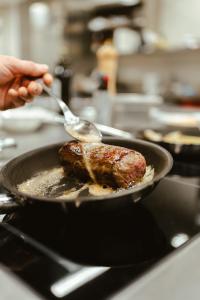 a person is cooking a piece of meat in a pan at Villa Bavaria in Merano