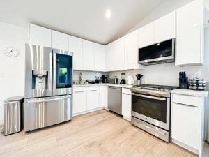 eine Küche mit weißen Schränken und Küchengeräten aus Edelstahl in der Unterkunft Modern 2BR Oasis - Cal-Cal in Calabasas