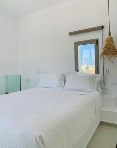 Casa di Amerissa Premium Accommodation في سكيروس: سرير ابيض مع مخدات بيضاء ونافذة