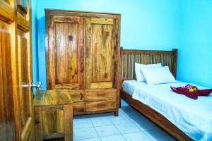 a small bedroom with a bed and a wooden door at KJ Purple Gate SENGGIGI in Senggigi 