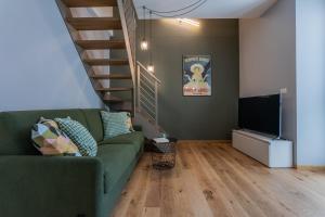 a living room with a green couch and a staircase at Le Casette del Balon by Wonderful Italy in Turin