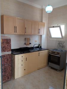 a kitchen with wooden cabinets and a sink and a window at الغردقه البحر الاحمر مبارك 6 in Hurghada