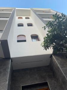 a tall white building with windows and a tree at Residence Al-Bahr in M'diq