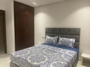 a bedroom with a large bed with blue and white sheets at Residence Al-Bahr in M'diq