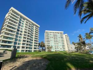 two tall buildings on a beach with palm trees at Mayan Playa Departamento Uxmal in Acapulco