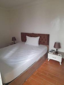 a bedroom with a large white bed and two lamps at Chez ouaki in Salé