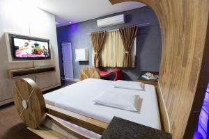 um quarto com uma cama e uma televisão na parede em Troia Motel em Foz do Iguaçu