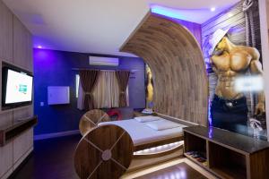 a room with a bed and a painting of a muscular man at Troia Motel in Foz do Iguaçu