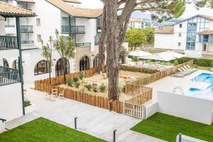 un patio de apartamentos con un árbol y una piscina en Residence Ibaia, en Hendaya