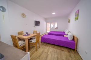 a bedroom with a purple bed and a table at Apartmani Šarović Tara in Rača