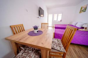 a dining room with a table and a purple bed at Apartmani Šarović Tara in Rača +2 photos