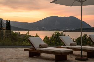 SpartokhórionVilla Erini的两把躺椅和一把雨伞在湖前