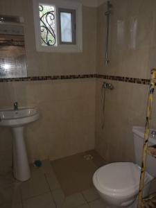 een badkamer met een toilet, een wastafel en een raam bij Keur Baboune in Mbour