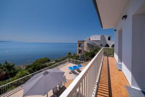 a balcony with an umbrella and chairs and the ocean at Villa Fertilia 8 posti letto - Key to Villas in Fertilia