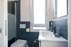 a bathroom with a sink and a toilet and a window at Villa Fertilia 8 posti letto - Key to Villas in Fertilia