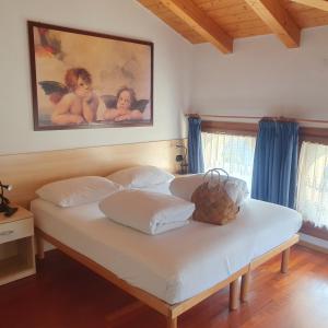 1 dormitorio con 1 cama blanca y una pintura en la pared en GARDAINN La CASCINA, en Riva del Garda