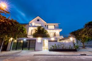 une maison blanche éclairée la nuit dans l'établissement villa long cung gần biển 7 phòng ngủ VIP, à Vung Tau