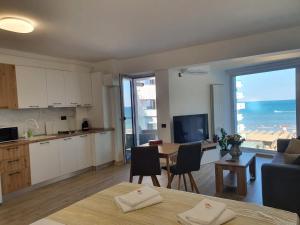 a living room with a kitchen and a table with chairs at Alee Infinity Pool & Spa in Mamaia Sat/Năvodari