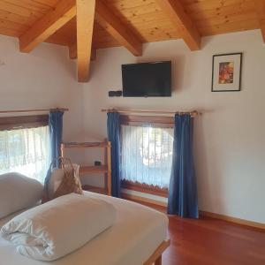 a bedroom with a bed and a flat screen tv at GARDAINN La CASCINA in Riva del Garda