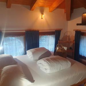 a bedroom with two beds with white sheets and blue curtains at GARDAINN La CASCINA in Riva del Garda