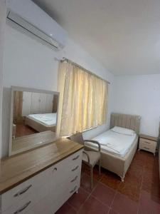 ein Schlafzimmer mit einem Spiegel, einem Bett und einer Kommode in der Unterkunft Hotel Gjika in Sarandë
