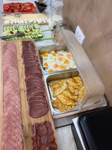 a buffet of food with eggs and sausage and meat at Apart-Hotel President in Ulcinj