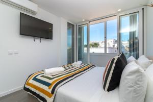 a bedroom with a white bed with a flat screen tv at Casa Ayla in Carvoeiro