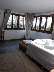 2 camas en un dormitorio con ventanas y alfombra en Casa Mar, en Tatajuba
