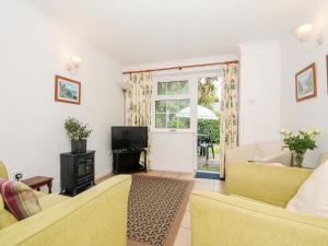 a living room with two yellow chairs and a television at Forge Cottage in Helston