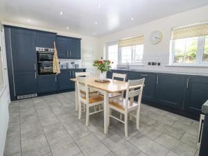 a kitchen with blue cabinets and a table and chairs at Cynefin in Llangefni