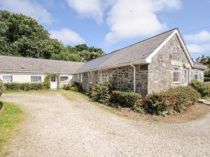 an old stone house with a gravel driveway at Forge Cottage in Helston