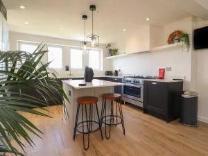 a kitchen with a island and two bar stools at Dunster Cottage in Clitheroe