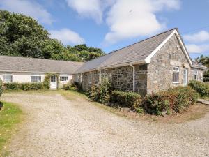 an old stone house with a gravel driveway at Dairy Cottage in Helston