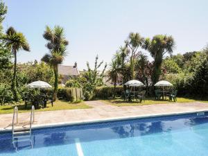 a swimming pool with tables and chairs and umbrellas at Dairy Cottage in Helston